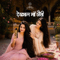 Two women in traditional attire with a kesh krti hair serum bottle of shampoo in a decorative setting.