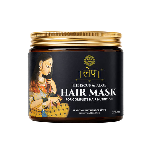 a premium amber glass jar of lep hibiscus and aloe hair mask for complete hair nutrition with a golden cap. the sleek black product label features traditional indian artwork of a woman combing her long dark hair, elegant gold typography, and the text "traditionally handcrafted, freshly made for you" in 250gm volume.